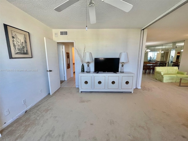 living room featuring a textured ceiling, light colored carpet, and ceiling fan