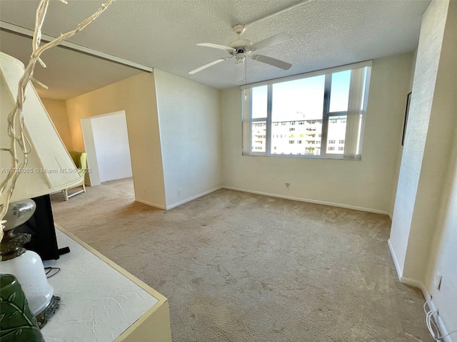 unfurnished room with ceiling fan, light carpet, and a textured ceiling