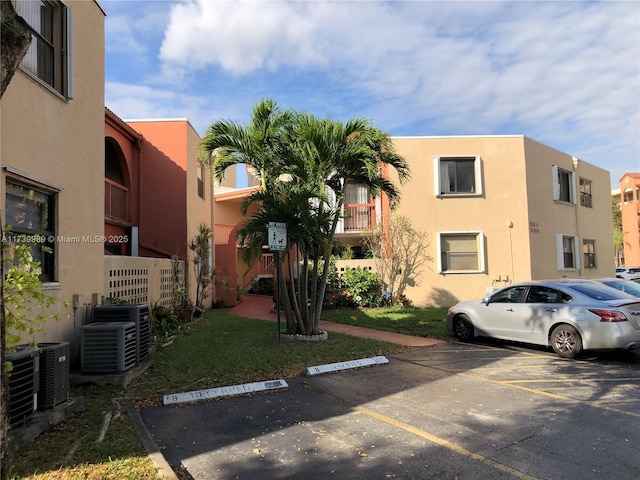 view of building exterior featuring uncovered parking and cooling unit