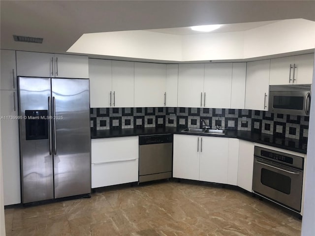 kitchen featuring tasteful backsplash, appliances with stainless steel finishes, sink, and white cabinets