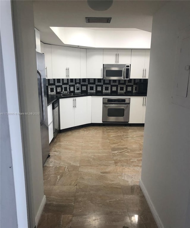 kitchen with white cabinetry, stainless steel appliances, electric panel, and backsplash