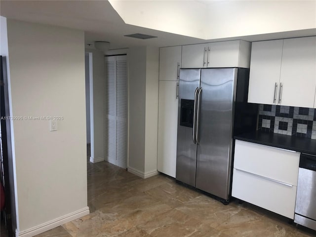 kitchen with decorative backsplash, white cabinets, and appliances with stainless steel finishes