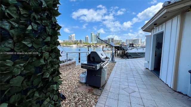 view of patio / terrace with a water view, a grill, and a boat dock