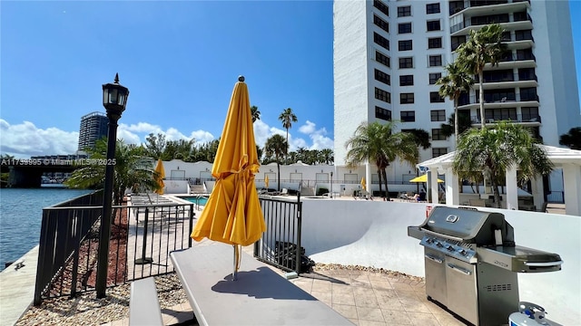 view of patio / terrace featuring a water view, a grill, and a community pool