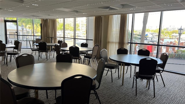 carpeted dining area with floor to ceiling windows, a healthy amount of sunlight, and a paneled ceiling