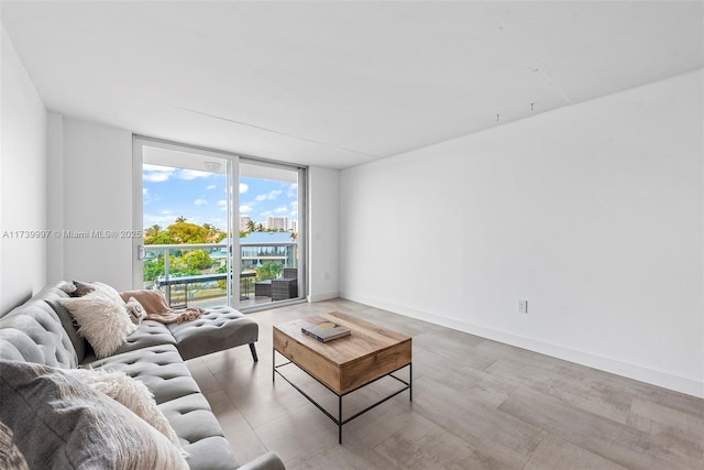 living room with floor to ceiling windows, light wood finished floors, and baseboards