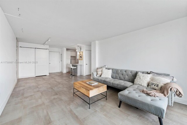 living area featuring a barn door and baseboards