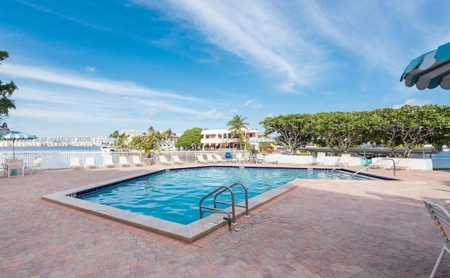 pool with a patio area and fence