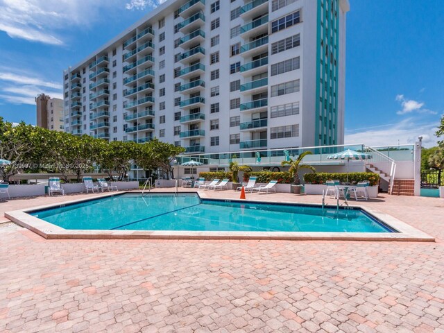 view of swimming pool with a water view and a patio area