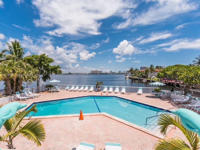 community pool featuring a water view, a patio area, and fence