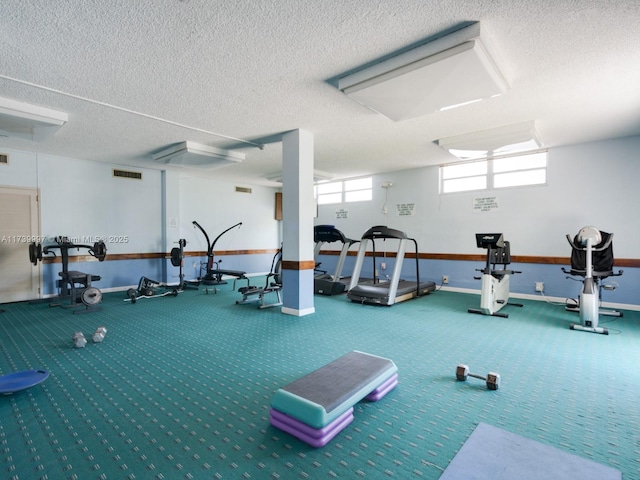 exercise room featuring a textured ceiling, visible vents, and baseboards