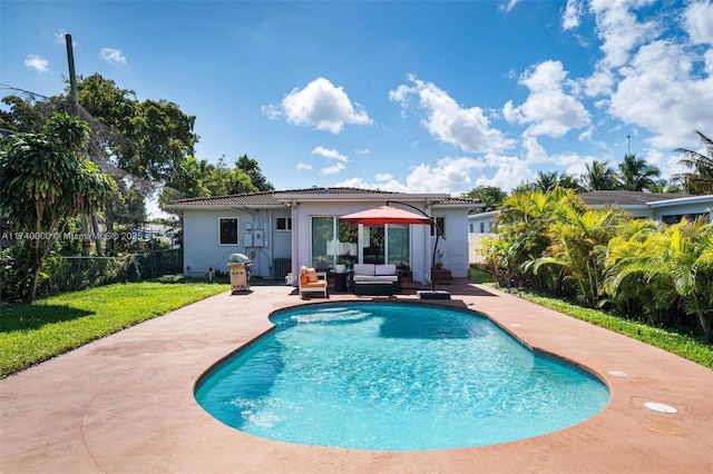 rear view of house with outdoor lounge area, a fenced in pool, a patio area, and a lawn