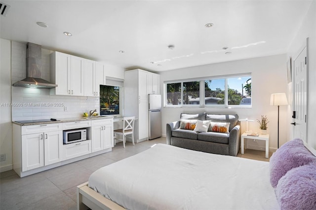 bedroom with stainless steel fridge, sink, and light tile patterned floors