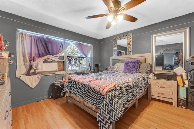 bedroom with cooling unit, ceiling fan, and light hardwood / wood-style floors