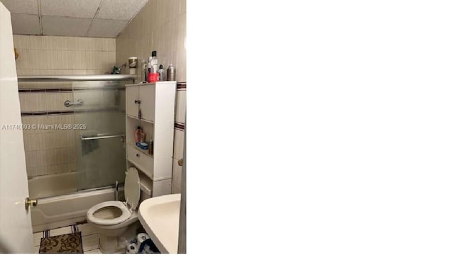 bathroom featuring enclosed tub / shower combo and toilet