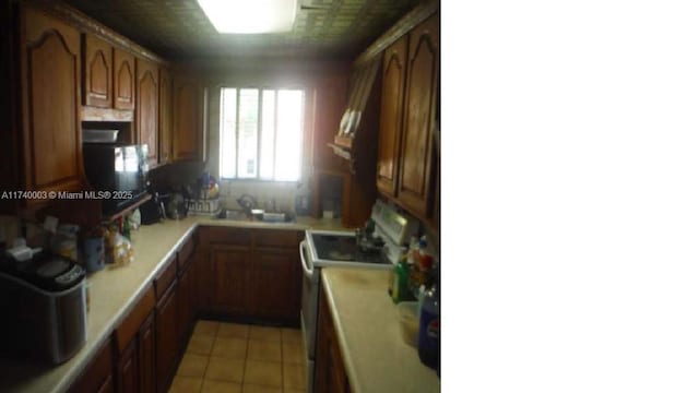 kitchen featuring light tile patterned floors, decorative backsplash, sink, and range