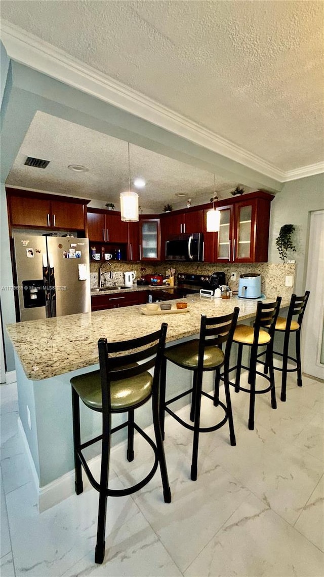 kitchen with light stone counters, appliances with stainless steel finishes, decorative light fixtures, and decorative backsplash