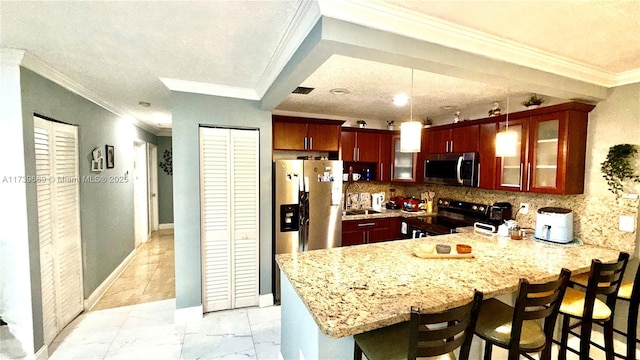 kitchen with appliances with stainless steel finishes, decorative light fixtures, kitchen peninsula, and a breakfast bar area