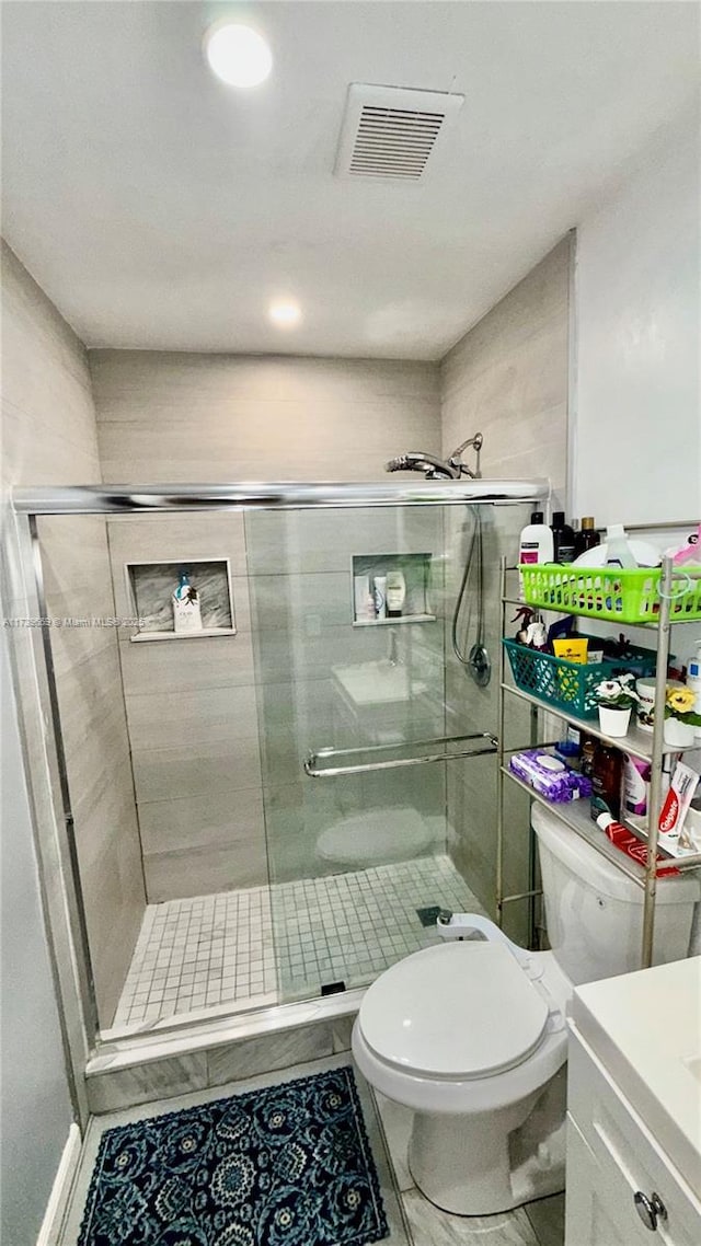 bathroom featuring vanity, walk in shower, and toilet