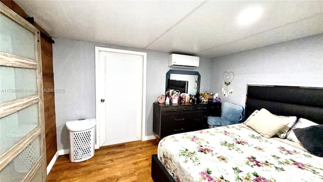 bedroom with a wall mounted air conditioner and light hardwood / wood-style flooring