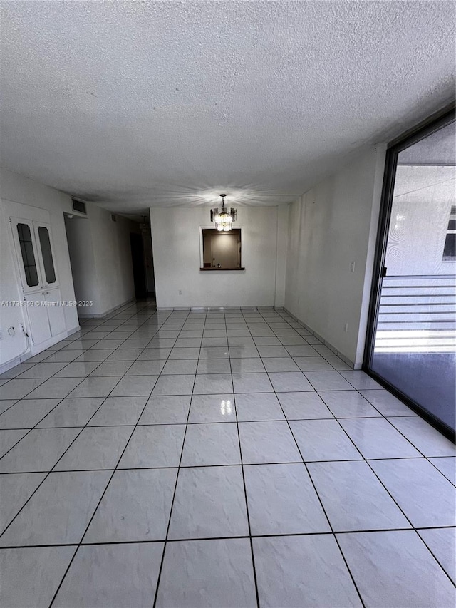 empty room featuring a textured ceiling and light tile patterned flooring