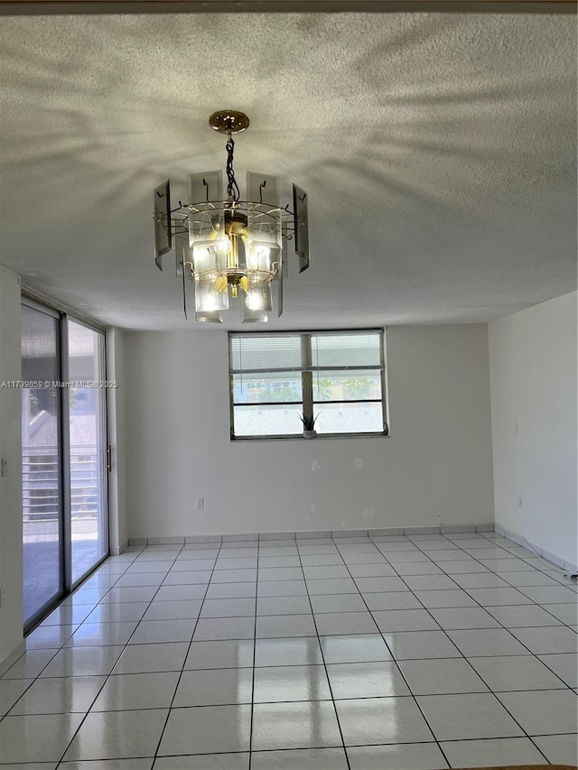 spare room with a notable chandelier, a textured ceiling, and light tile patterned floors