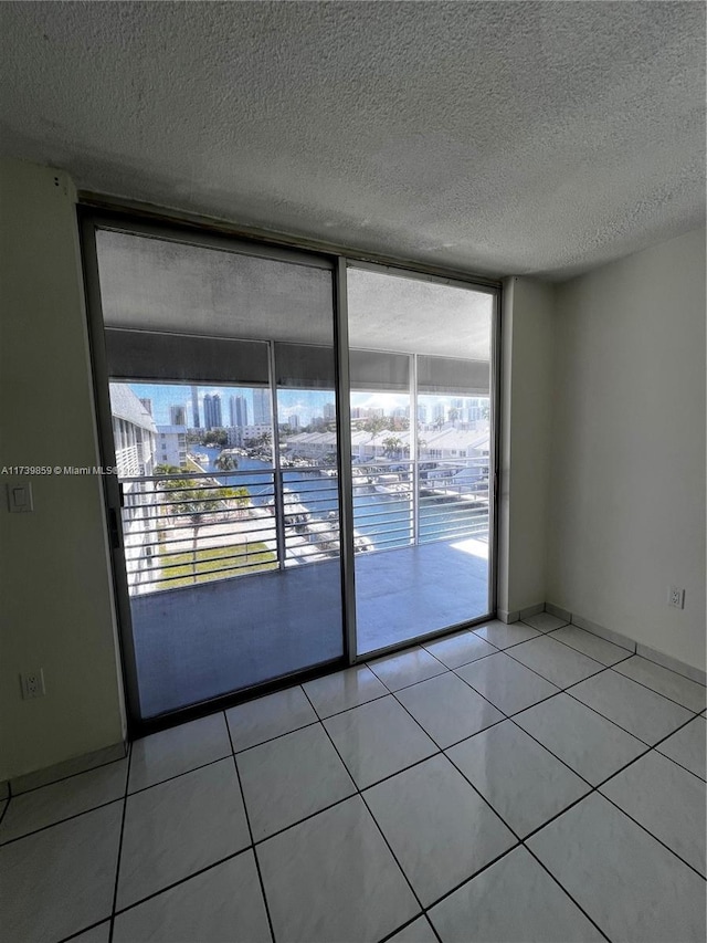 spare room with light tile patterned floors, a wall of windows, and a textured ceiling