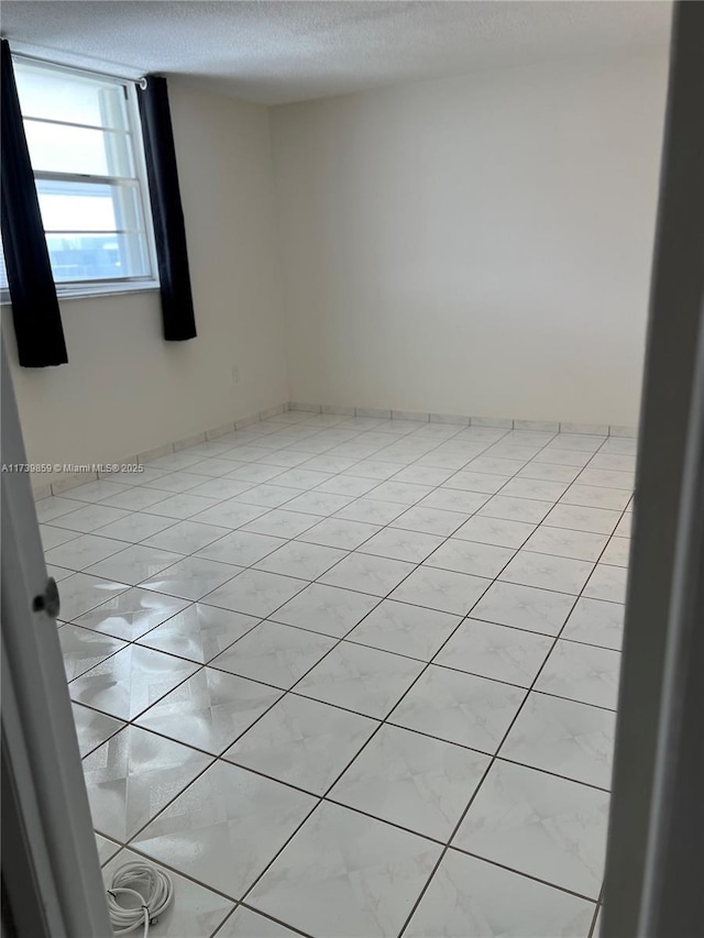 tiled empty room featuring a textured ceiling