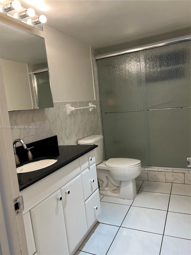 bathroom featuring walk in shower, tile patterned floors, toilet, tile walls, and vanity