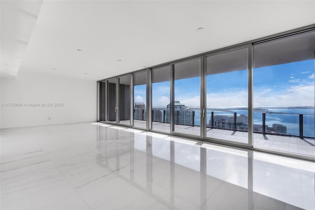 unfurnished room with a water view and floor to ceiling windows