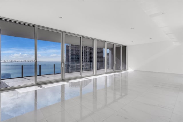 unfurnished room with a wall of windows and a water view