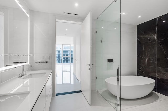 bathroom featuring vanity, a tub, and tile walls