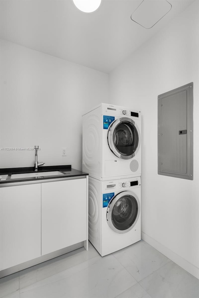 clothes washing area with stacked washer / dryer, sink, electric panel, and cabinets