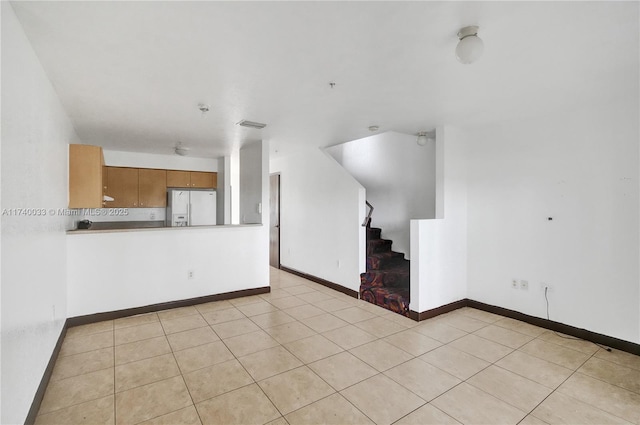 unfurnished living room with light tile patterned floors, baseboards, and stairs