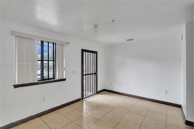 tiled empty room with visible vents and baseboards