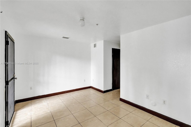 empty room with visible vents, baseboards, and light tile patterned flooring