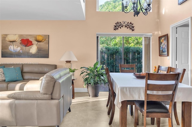 dining room featuring baseboards, a high ceiling, and an inviting chandelier