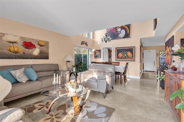 living area with a towering ceiling, baseboards, and a chandelier