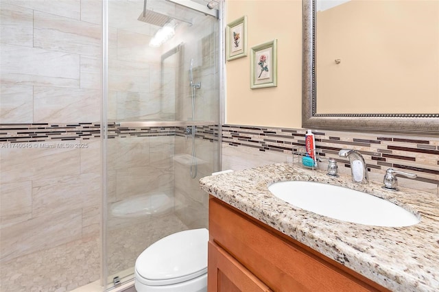 full bathroom featuring toilet, a wainscoted wall, vanity, a shower stall, and tile walls