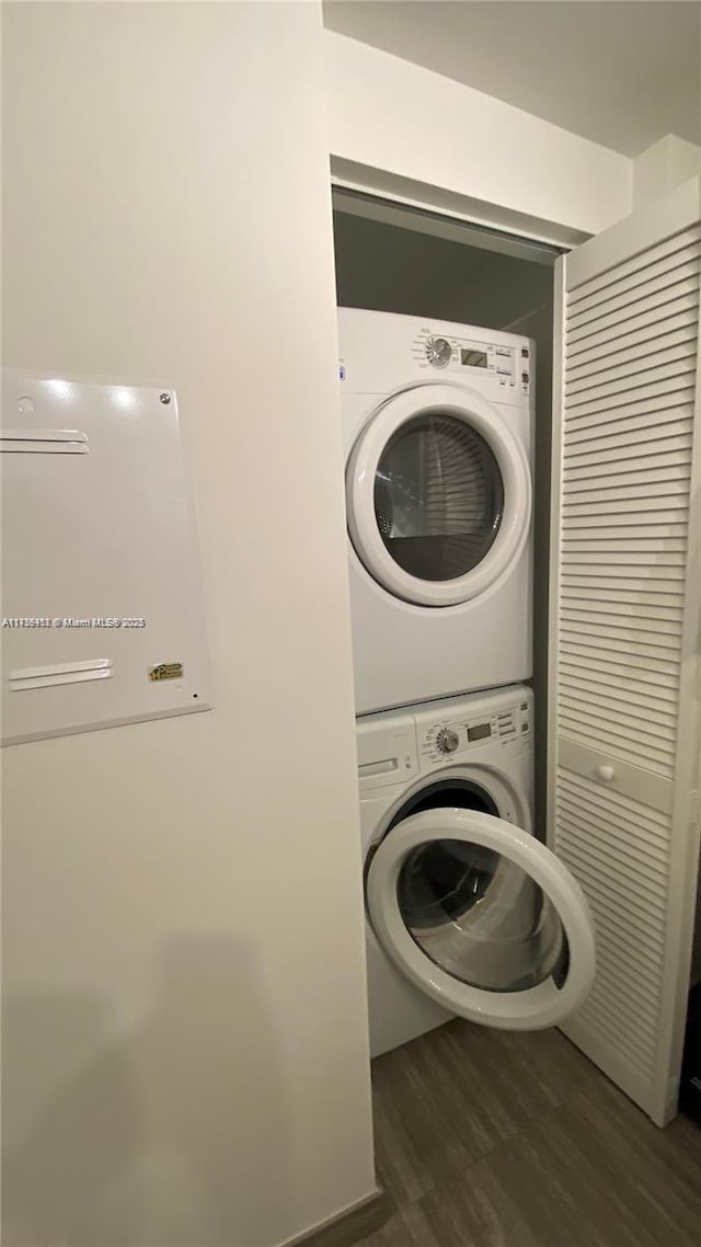 laundry room with stacked washer / dryer and dark wood-type flooring