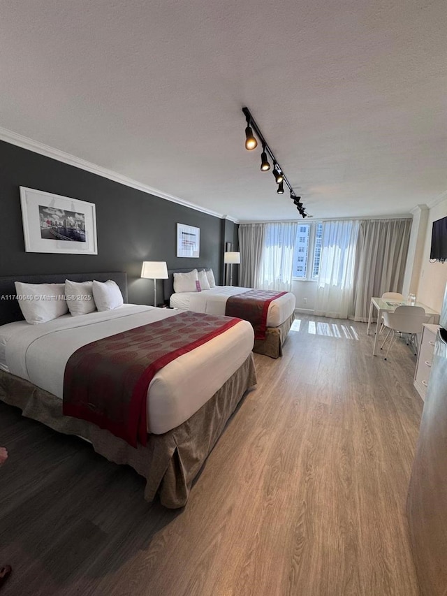 bedroom featuring crown molding, light hardwood / wood-style flooring, and a textured ceiling