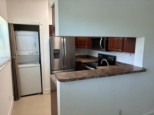 620 Cypress Club Way Unit I13, Deerfield Beach, FL 33064 - kitchen featuring stainless steel appliances, stacked washing machine and dryer, dark countertops, a peninsula, and light tile patterned floors