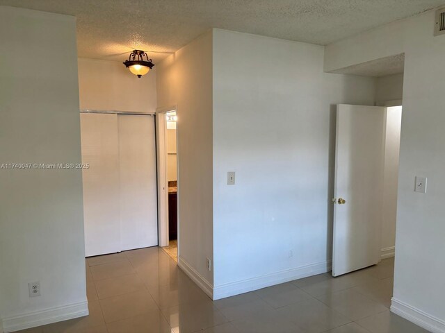 620 Cypress Club Way Unit I13, Deerfield Beach, FL 33064 - unfurnished bedroom with a textured ceiling, baseboards, tile patterned floors, and a closet
