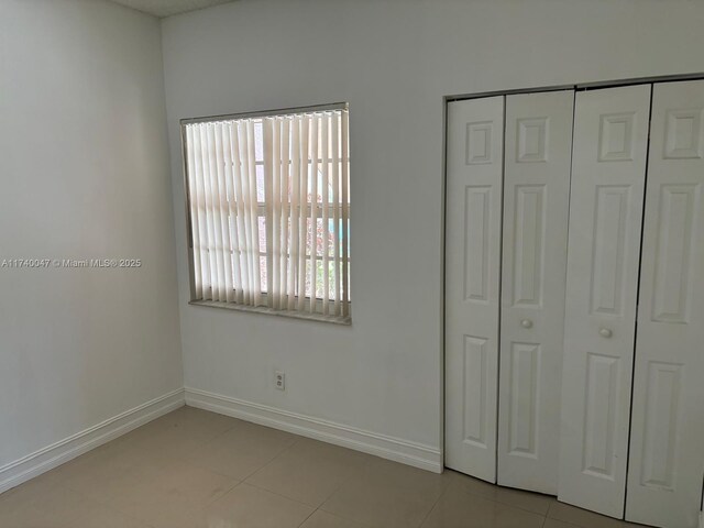 620 Cypress Club Way Unit I13, Deerfield Beach, FL 33064 - unfurnished bedroom featuring a closet, light tile patterned floors, and baseboards