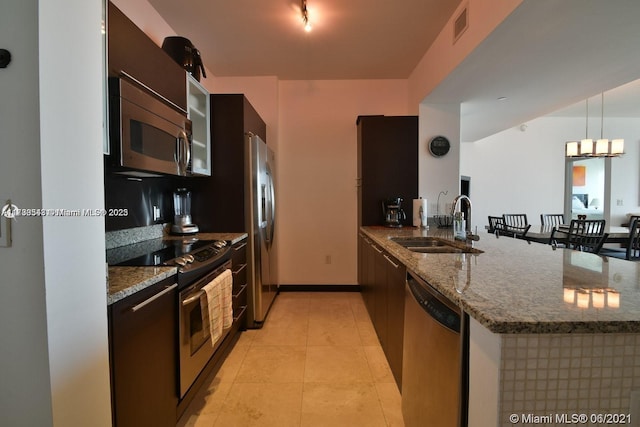 kitchen featuring appliances with stainless steel finishes, sink, kitchen peninsula, and dark stone counters