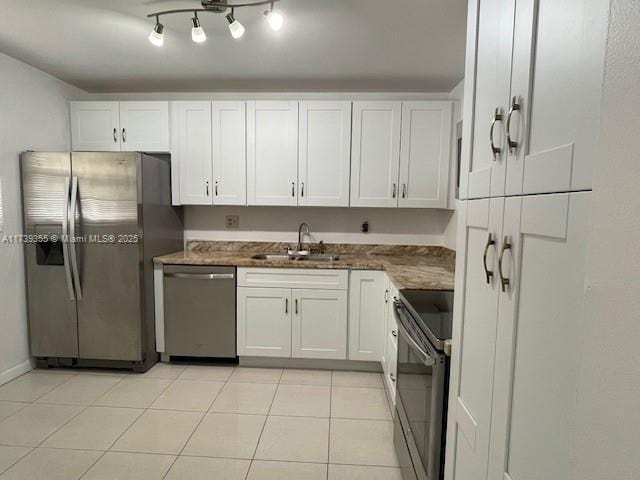 kitchen with white cabinetry, stainless steel appliances, light tile patterned flooring, and sink