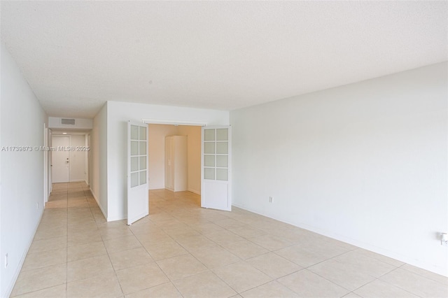 tiled spare room with a textured ceiling and french doors