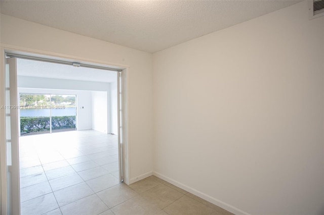 hallway with a textured ceiling and light tile patterned floors