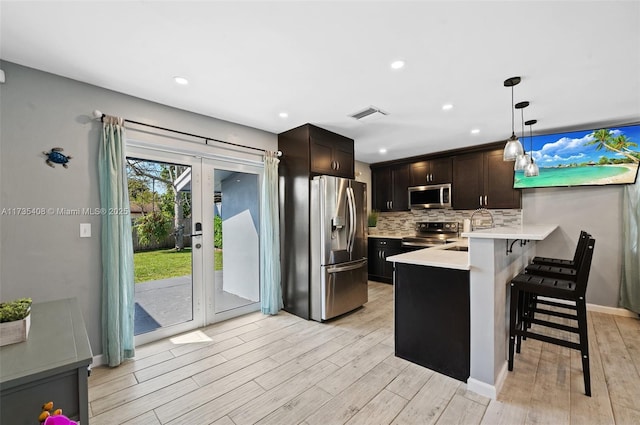 kitchen featuring dark brown cabinetry, hanging light fixtures, a kitchen breakfast bar, kitchen peninsula, and stainless steel appliances