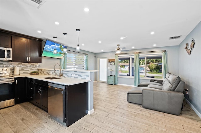 kitchen featuring sink, appliances with stainless steel finishes, tasteful backsplash, light hardwood / wood-style floors, and decorative light fixtures